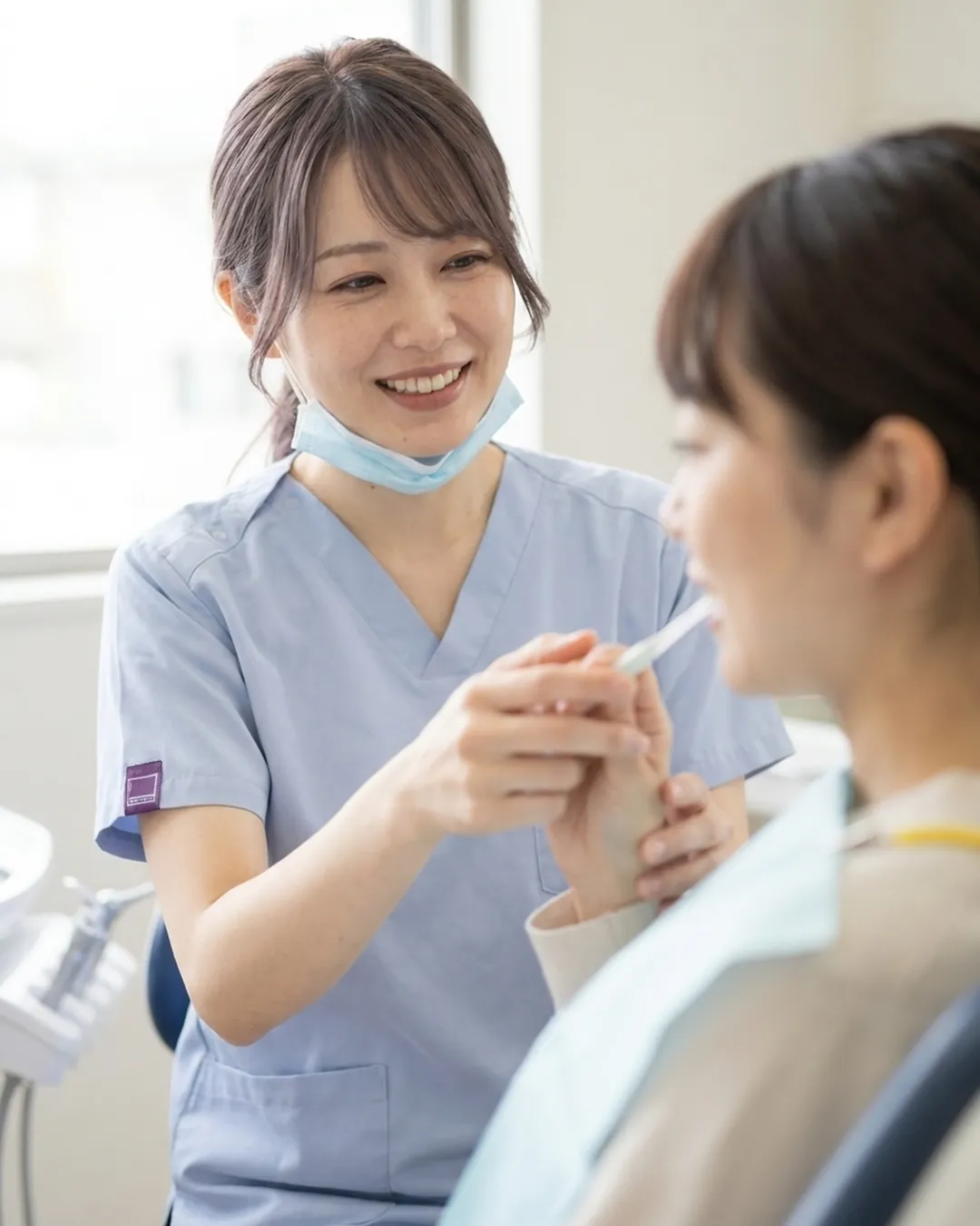 歯ブラシの持ち方を、患者さんの手を添えて教える歯科衛生士