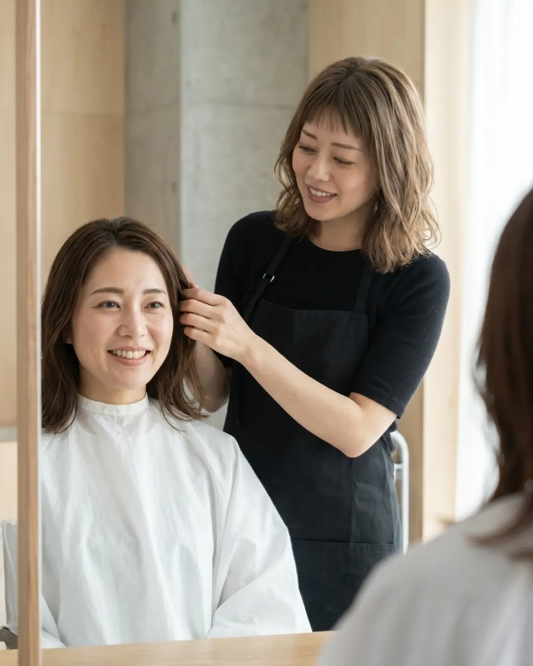 鏡越しに会話しながらお客様の髪に触れる美容師