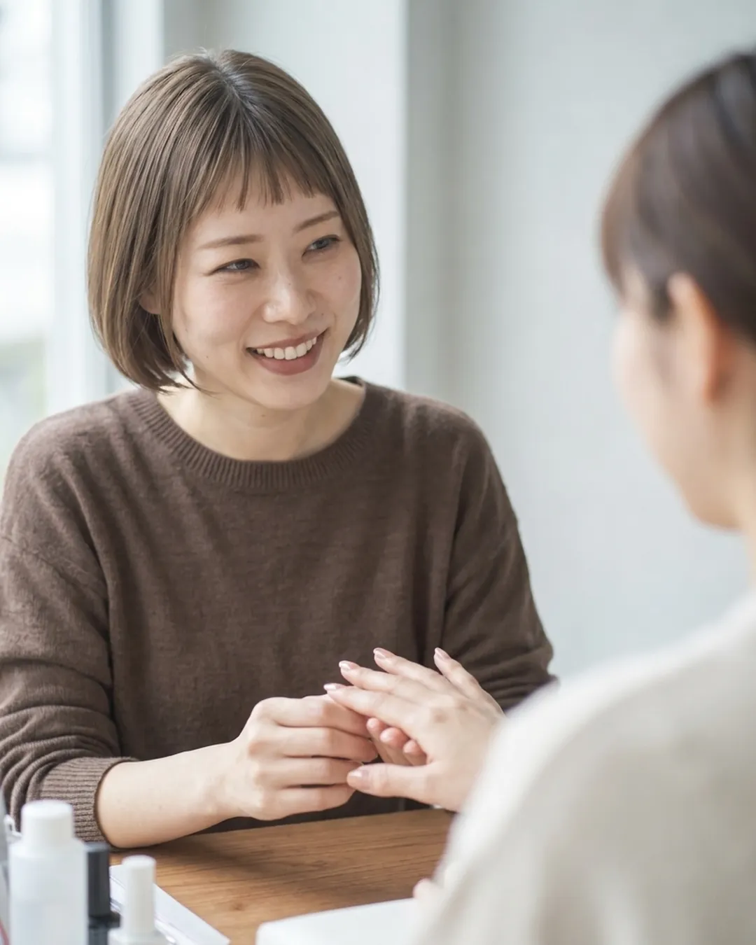 仕上がったネイルを、お客様の手を取って確かめるネイリスト