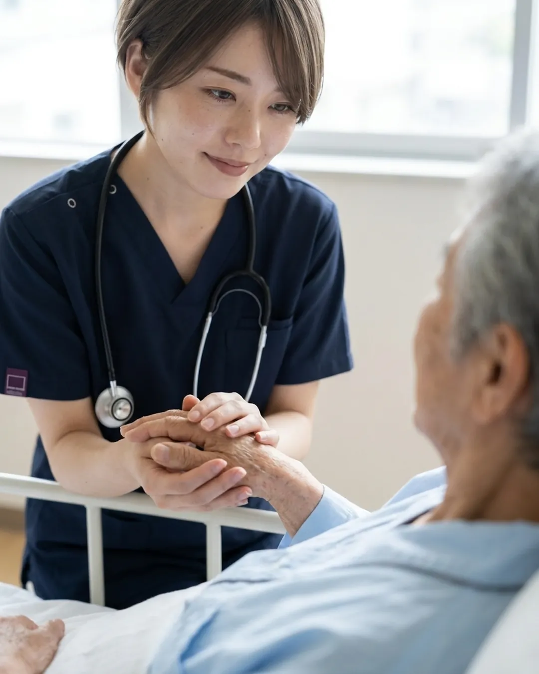 病棟で患者さんの手を両手で包む看護師